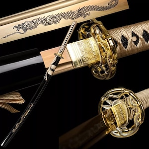 May include: A gold-colored katana sword with a black scabbard and a white and gold handle. The sword has a dragon design on the scabbard and a gold-colored tassel.