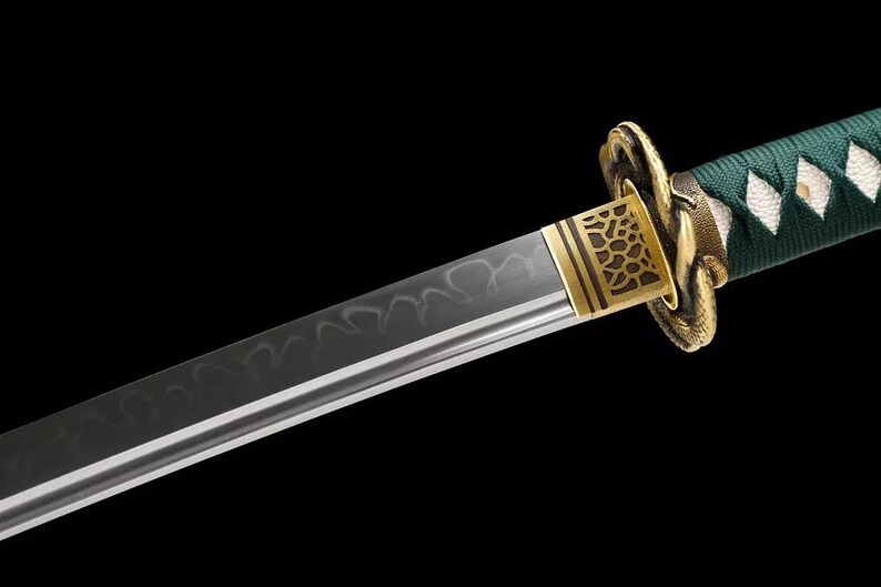 May include: Close-up of a Japanese katana sword. The blade has a wavy pattern and a sharp edge. The hilt is wrapped in green fabric with white diamond-shaped accents. The guard is gold-colored with an intricate design.
