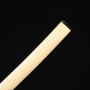 May include: Angled view of a light-colored, cylindrical object against a black background. The object has a smooth, off-white surface and a black, rectangular tip. The object is positioned diagonally across the frame.