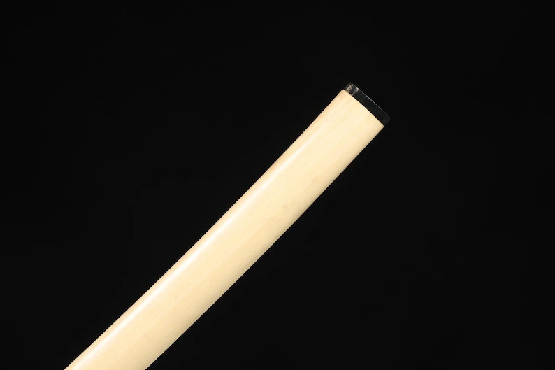 May include: Angled view of a light-colored, cylindrical object against a black background. The object has a smooth, off-white surface and a black, rectangular tip. The object is positioned diagonally across the frame.