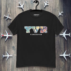 May include: Black t-shirt with a graphic of the letters YVR in a vintage college style font. The letters are filled with a sunset scene. The text "Vancouver" is below the letters.