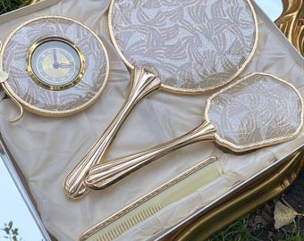 FINER TEMPTRESS - Sminkbordsset i vintage Regency Hollywood-stil. Oanvänd hårborste, spegel, klocka och kam i guldfärgad ask.