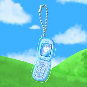Puede incluir: Un llavero de acrílico transparente con forma de teléfono plegable y acabado azul brillante. La pantalla muestra un corazón blanco con el texto "Welcome" y "HIN4". El teclado incluye números y símbolos. Una cadena de bolas está unida a la parte superior.