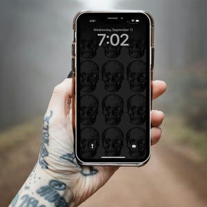 Pode incluir: Um smartphone com fundo preto e um padrão de caveiras brancas. A hora é 7:02 e a data é quarta-feira, 11 de setembro.