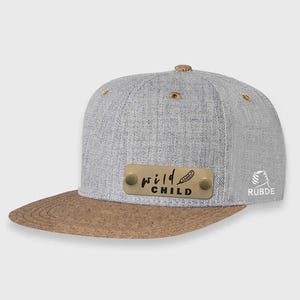 May include: Gray and brown baseball cap with a gold metal plate that says "wild child" with a feather design. The cap has a brown brim and a gray crown.