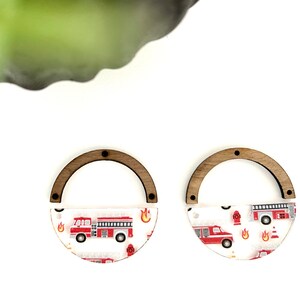 Peut inclure: Une paire de boucles d'oreilles en bois et en acrylique avec un motif de camion de pompiers et de borne d'incendie. Les boucles d'oreilles sont des demi-cercles avec un dessus en bois et un fond en acrylique transparent.