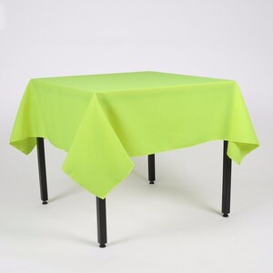 May include: A bright green square tablecloth draped over a table with black legs. The tablecloth is made of a smooth, wrinkle-resistant fabric.