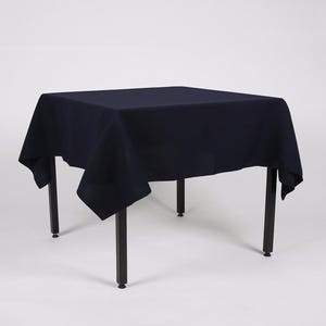 May include: A dark blue square tablecloth draped over a black metal table with four legs.