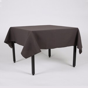 May include: A dark grey square tablecloth draped over a table with black legs. The tablecloth has a smooth, even texture.