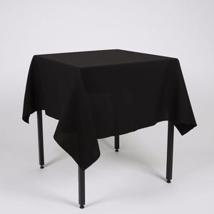 May include: A black square tablecloth draped over a table with black metal legs.