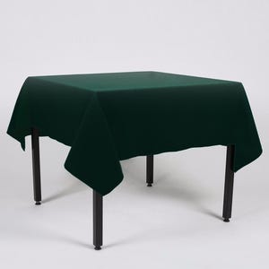 May include: A dark green square tablecloth draped over a table with black legs.