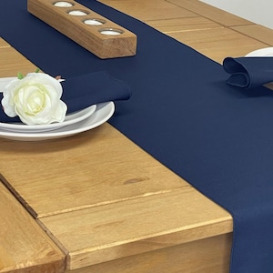May include: A navy blue table runner with a wooden candle holder on a light brown wooden table. The table runner is 35.5 cm wide and 177.8 cm long.