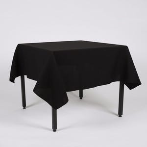 May include: Black square tablecloth draped over a black metal table with four legs.