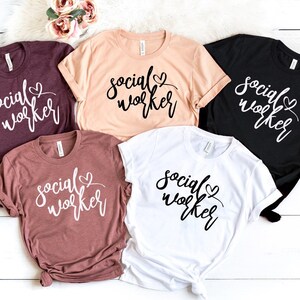 May include: Five t-shirts with the text "social worker" in different colors, including maroon, peach, black, and white.