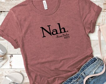 May include: A maroon t-shirt with the text "Nah." and the quote "Rosa Parks 1955" printed on the front.