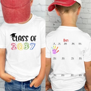 May include: White t-shirt with "Class of 2037" in black, yellow, pink, and blue. The back features a handprint and school years from K to 12th grade, with the name "Ben" above the handprint.