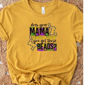 May include: A yellow t-shirt with the text "Does your mama know how you got those beads?" in black, purple, and green lettering. The text is surrounded by purple and green beads.