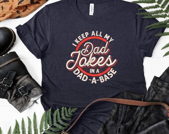 May include: A navy blue t-shirt with a white circle graphic that says "I keep all my Dad Jokes in a Dad-A-Base".