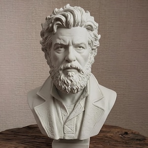 May include: A white matte bust sculpture of a middle-aged person with a full beard and wavy hair, wearing a collared jacket with a textured lapel. The sculpture features detailed facial expressions, including deep-set eyes and a defined brow.