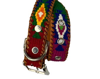 May include: A colorful dog collar with a geometric pattern in shades of red, blue, green, yellow, and white. The collar is made of leather and has a silver buckle.