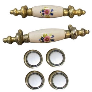 May include: Two sets of vintage cabinet knobs with floral designs. The knobs are made of ceramic with gold accents. Each set includes two knobs and two pulls.