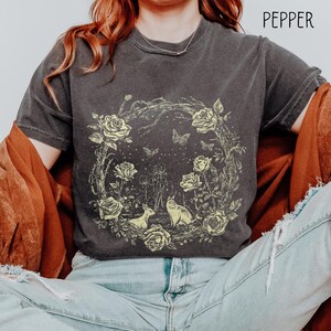 May include: Dark gray t-shirt with a floral and animal graphic. The design features yellow roses, butterflies, and two animals within a circular wreath. The word "PEPPER" is printed at the top right.