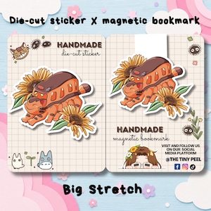 May include: A die-cut sticker and a magnetic bookmark featuring a cat-shaped bus character with orange fur and brown stripes, surrounded by yellow sunflowers and green leaves. The items are displayed on grid-patterned backing cards with text.