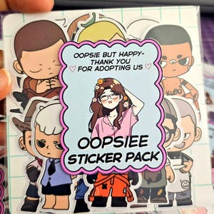 May include: A pack of colorful stickers featuring cartoon characters. The central sticker has a woman with glasses and flowers in her hair, with the text "OOPSIEE STICKER PACK". Other stickers show various cartoon figures. The background is a grid pattern.