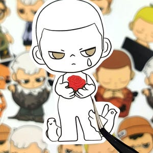 May include: A white sticker featuring a cartoon character holding a red rose. The character has a sad expression with a tear, and is surrounded by other cartoon figures. A pair of tweezers is holding the sticker.