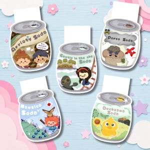 Op de afbeelding: Vijf magnetische boekenleggers in de vorm van frisdrankblikjes, elk met unieke illustraties en tekst: Arrietty Soda, Castle in the Sky Soda, Porco Soda, Nausicaa Soda en Ducksome Soda. Elke boekenlegger heeft een metallic grijze bovenkant.