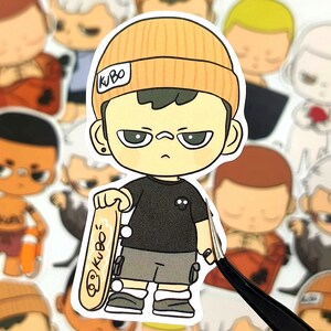 May include: A sticker featuring a cartoon character with an orange beanie, black t-shirt, and gray shorts. The character holds a skateboard with the text "KuBo". The sticker is surrounded by other similar cartoon stickers.