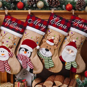 May include: Four Christmas stockings hang on a mantel, each personalized with a name: William, Mary, Elena, and Harry. The stockings feature festive designs, including a snowman, penguin, reindeer, and Santa Claus.