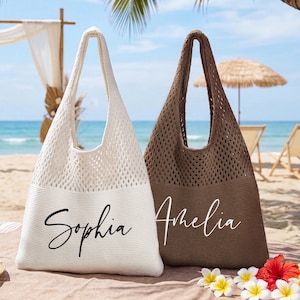 Puede incluir: Dos bolsas de playa, una crema y otra marrón, con un diseño de tejido abierto. La bolsa crema tiene el nombre "Sophia" en escritura negra, y la bolsa marrón tiene "Amelia" en escritura blanca. Las bolsas están en una playa con flores tropicales.