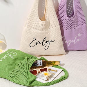 Pu&ograve; includere: Tre borse tote personalizzate in maglia color crema, lavanda e verde. La borsa color crema ha "Evelyn" in corsivo nero, la borsa lavanda ha "Angela" in corsivo bianco e la borsa verde ha "Olivia" in corsivo bianco. La borsa verde contiene occhiali da sole e una bottiglia.