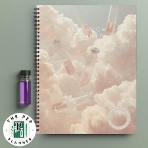Könnte beinhalten: Ein spiralgebundenes "Research Planner" Notizbuch mit einem wolkenartigen Hintergrund und schwebenden Reagenzgläsern. Eine kleine Glasflasche mit einer violetten Flüssigkeit befindet sich neben dem Planer. Ein kreisförmiges Logo mit Text und einer Stiftillustration befindet sich unten links.