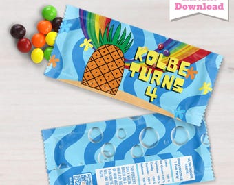 May include: Candy wrappers with a blue wave pattern, a rainbow, and a pineapple graphic. The text "KOLBE TURNS 4" is displayed. The wrappers are designed for a fun party and include nutritional facts.