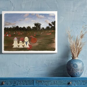 May include: A painting of three ghosts in a pumpkin patch. The ghosts are white and have black eyes. The pumpkins are orange and scattered across the field. The sky is blue with white clouds.