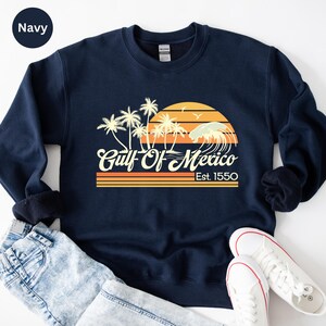 a navy sweatshirt with a sunset and palm trees on it