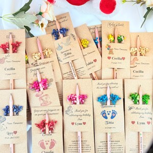 Puede incluir: Una colecci&oacute;n de recuerdos de fiesta personalizados con l&aacute;pices con detalles florales y tarjetas impresas. Las tarjetas incluyen nombres, fechas y frases como "Thank you for celebrating my birthday" y "Prima Comunione". Un coraz&oacute;n rojo con "I Love You" est&aacute; en el fondo.