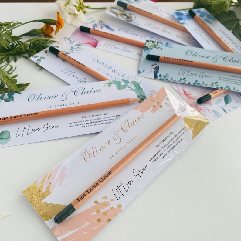 May include: A set of wedding favor pencils with a gold and pink design. The pencils are wrapped in clear plastic and have a brown wooden body with a green eraser. The pencils have the text "Let Love Grow" and "Oliver & Claire" printed on them. The date "20 April 2024" is also printed on the pencils.