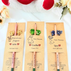 Puede incluir: Tres recuerdos de l&aacute;pices personalizados para la Primera Comuni&oacute;n, cada uno con un l&aacute;piz y adornos florales secos. Las tarjetas son de color marr&oacute;n claro con nombres y fechas, y los l&aacute;pices tienen el texto "Let Love Grow".