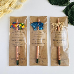 May include: Three pencils with dried flowers, packaged in brown paper with clear cellophane. Each pencil has the text "Let Love Grow" and a label that reads "Thank you for celebrating with us Oliver & Claire 20 April 2024".