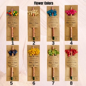 May include: A collection of eight pencils with attached dried flower bouquets in various colors. Each pencil is packaged with a brown card that includes the text "Thank you for celebrating with us Oliver & Claire" and "Let Love Grow."