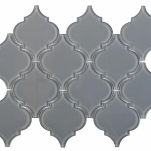 May include: Gray glass mosaic tiles in a quatrefoil pattern. The tiles are arranged in a staggered pattern to create a geometric design.