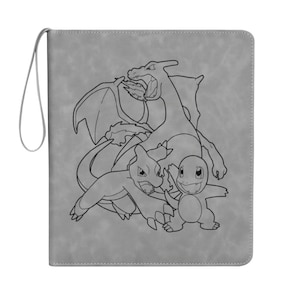 Può includere: Raccoglitore grigio con un disegno a tratto nero di tre draghi dei cartoni animati. Il raccoglitore ha un anello sul lato. I draghi sono in varie pose, uno dei quali sputa fuoco.