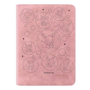 Könnte beinhalten: Ein rosa Kartenordner mit schwarzen Strichzeichnungen von Cartoon-Kreaturen in Kreisen. Der Name "Katharina" ist schwarz aufgedruckt, zusammen mit dem "TCGUARD"-Logo. Der Ordner hat eine strukturierte Oberfläche.