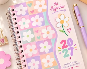 May include: A spiral-bound 2027 planner titled Mi Agenda with a pastel checkered pattern featuring white flowers and small hearts. The cover includes the text Mi Agenda, 2027, and Grandes Planes Para Un Año Increíble, accompanied by a single flower illustration.