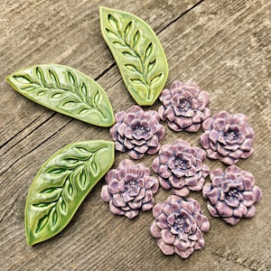 May include: A set of three ceramic mugs with a speckled, matte finish in cream, light grey, and dark grey. Each mug has a simple, minimalist design, suitable for coffee or tea.