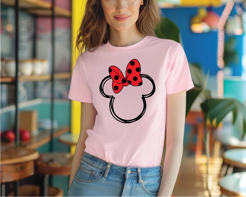 a woman wearing a pink shirt with a red minnie mouse head on it