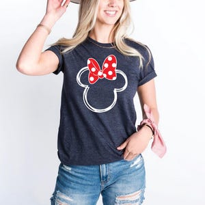a woman wearing a mickey mouse shirt and a hat